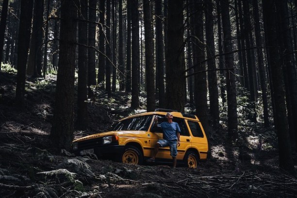 a car parked on pavement near a forest