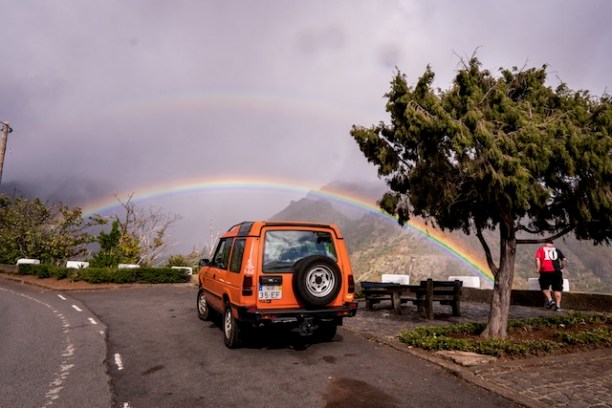 Land Rover 4x4 at a Madeira viewpoint with a double rainbow after the rain