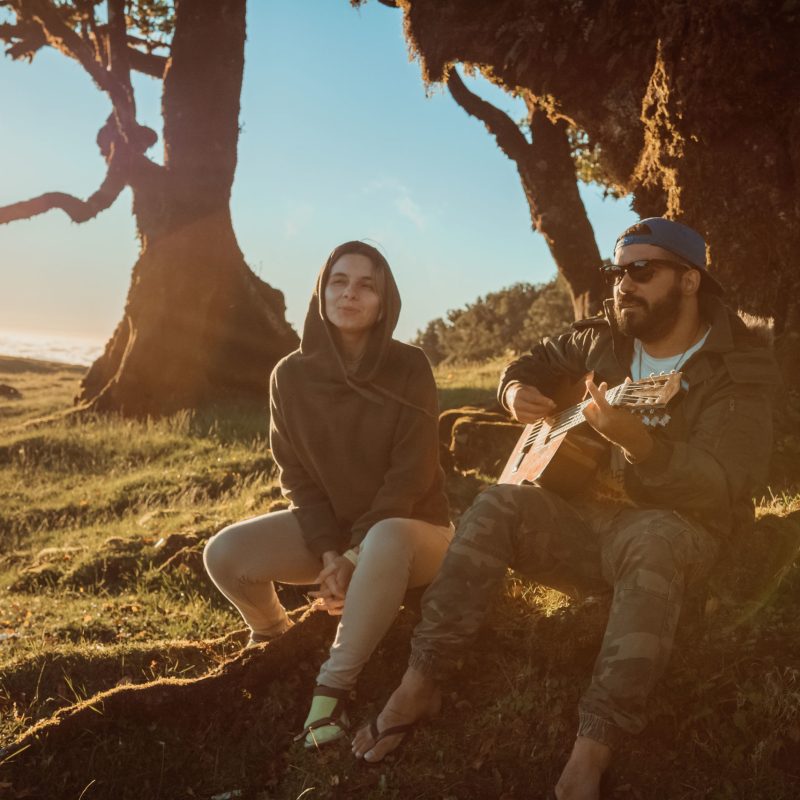 a man sitting on top of a grass covered field